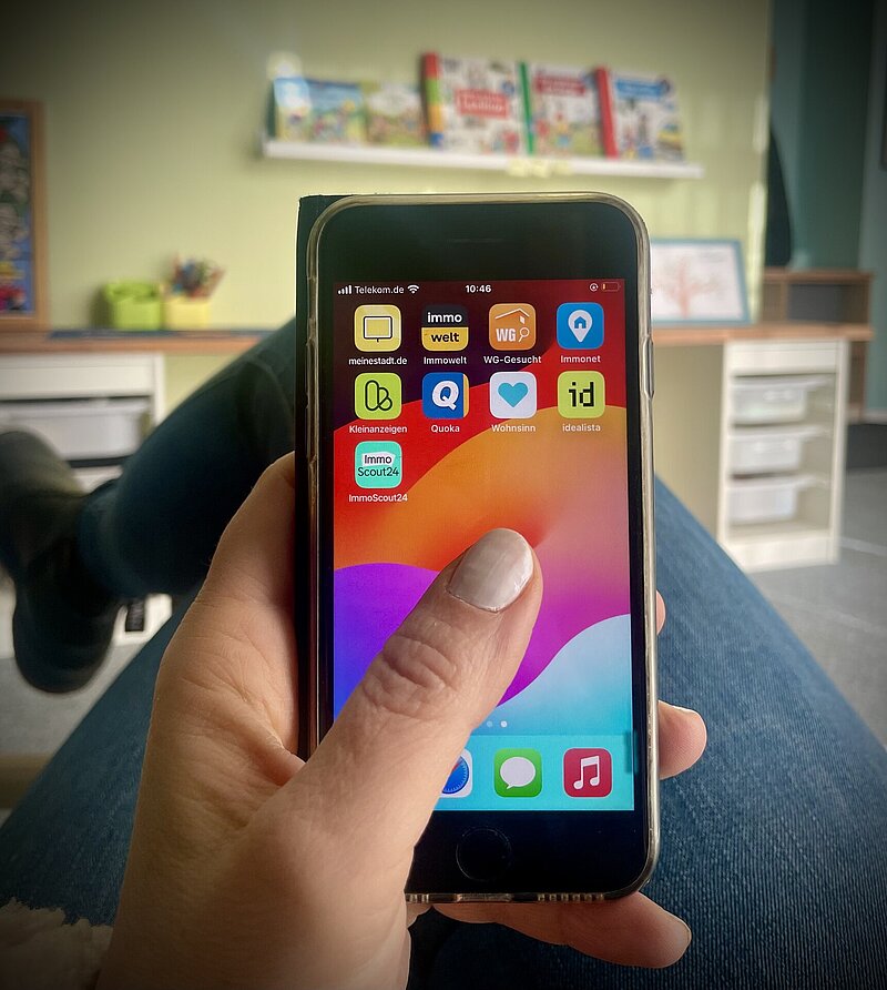 Eine sitzende Person hält ein Smartphone in der Hand